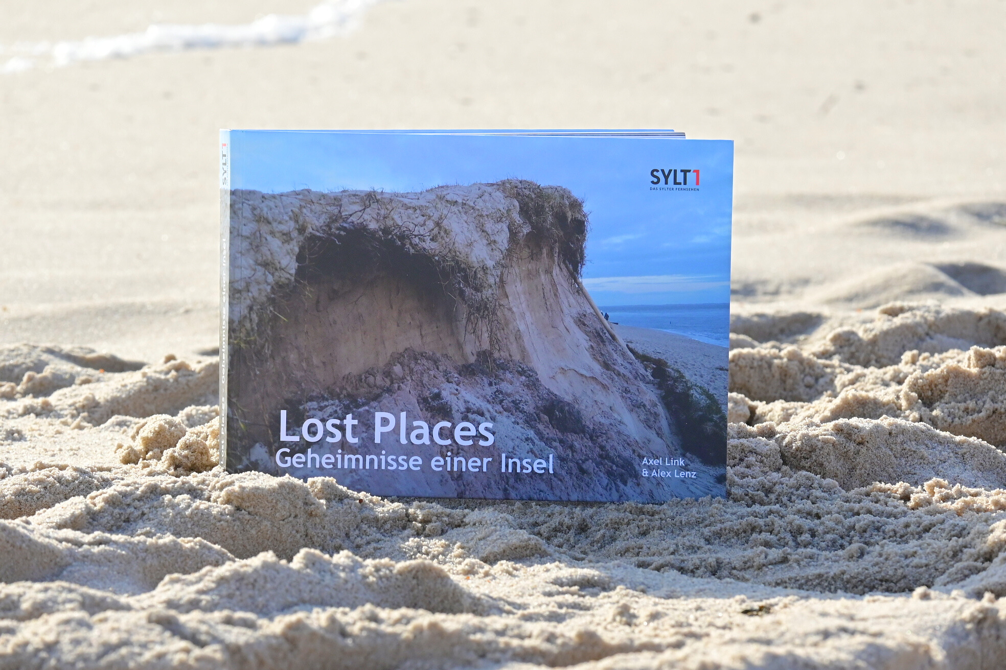 Buch Sylt Lost Places Geheimnisse einer Insel von Axel Link und Alex Lenz im Sand am Strand von Sylt